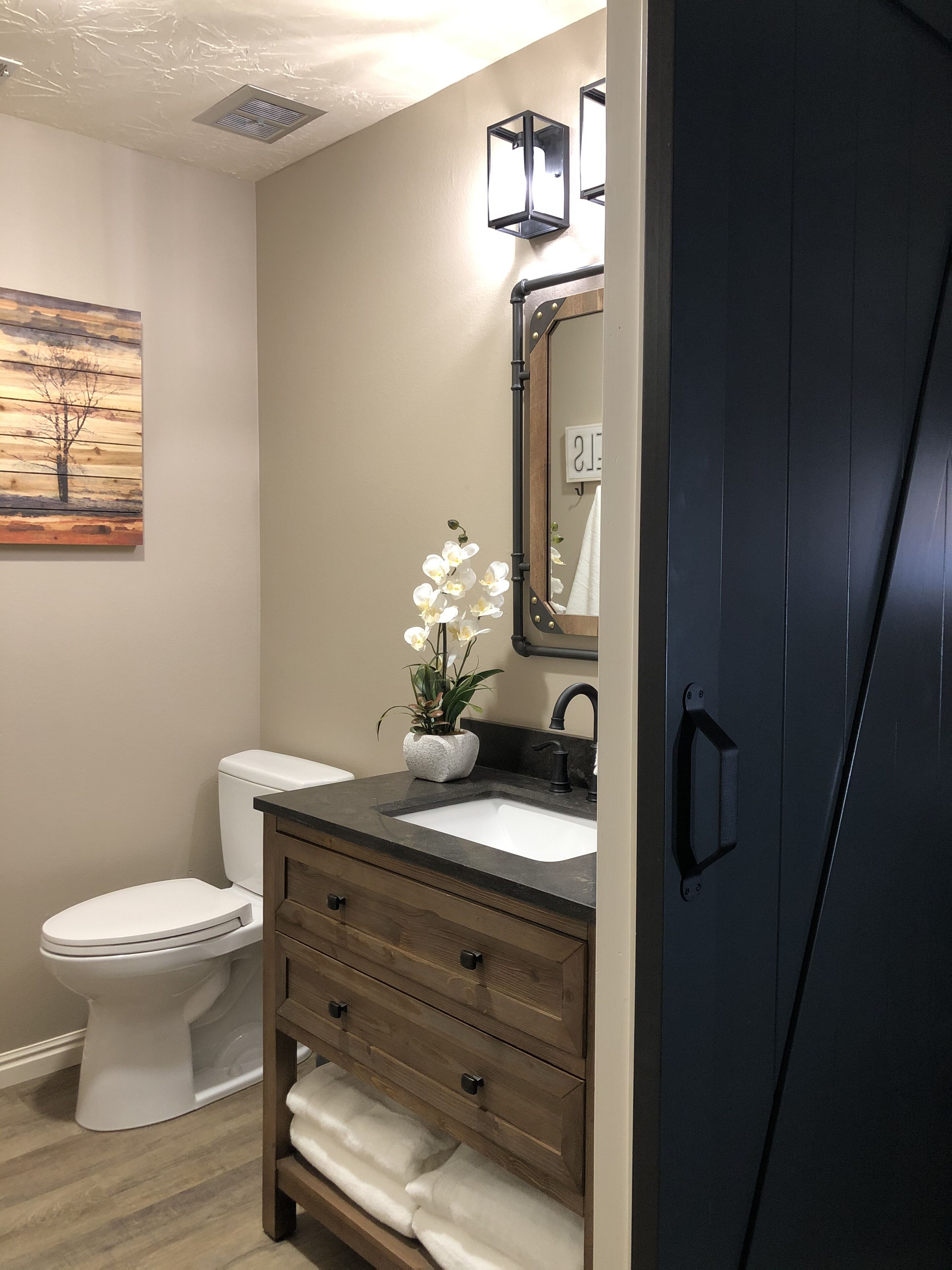 Un baño moderno con inodoro, tocador y espejo.