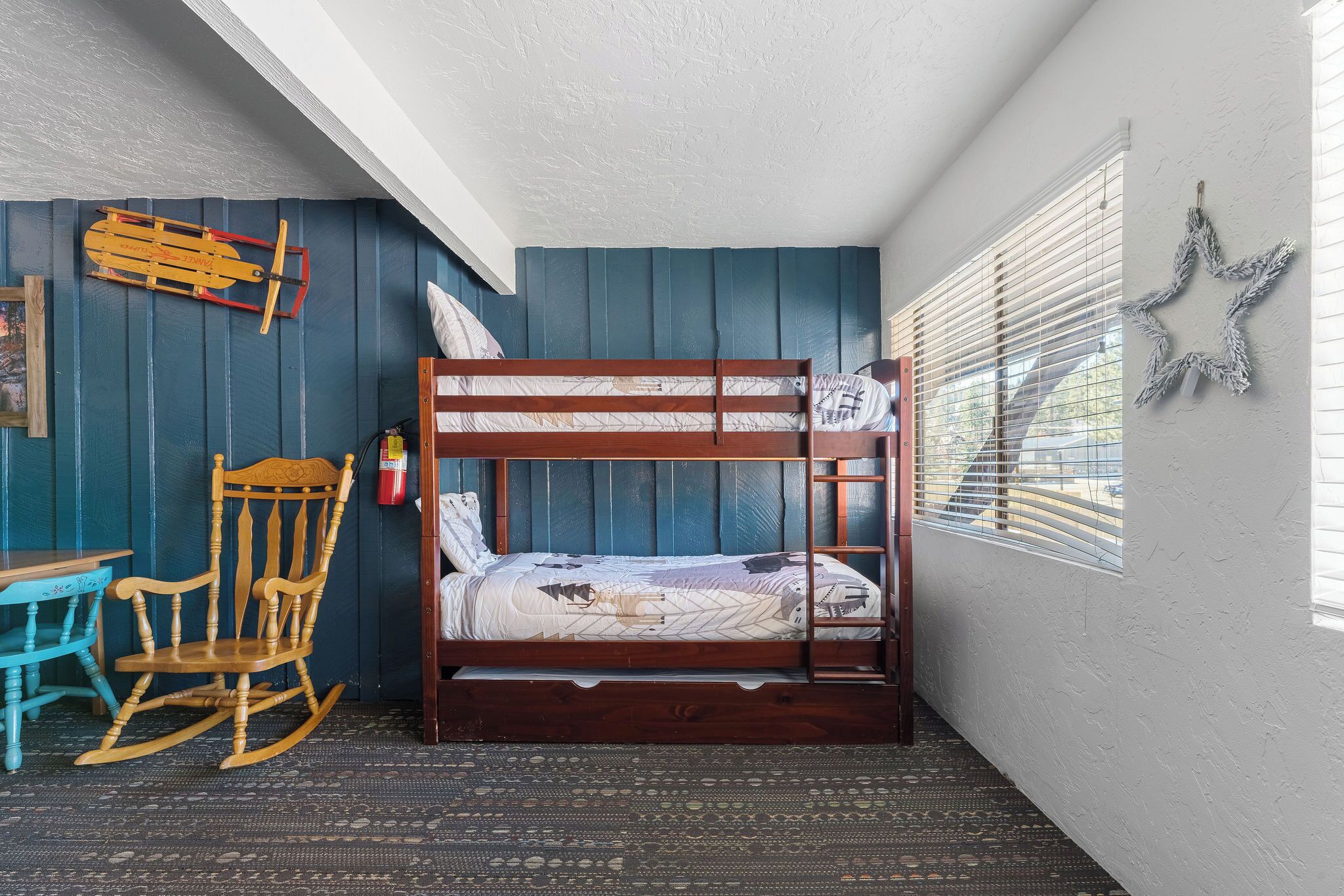 A bunk bed in a room with a blue wall, a rocking chair, and a star decoration.