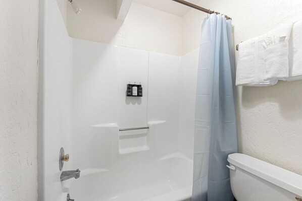 Un baño con una bañera blanca, cortina de ducha y un inodoro.