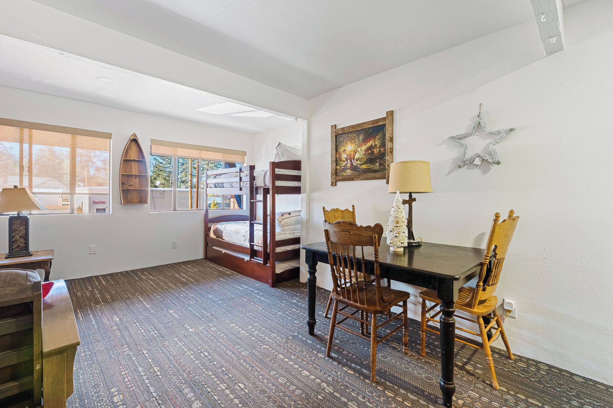 A room with a bunk bed, a desk with a chair, a lamp, and a star decoration on the wall.