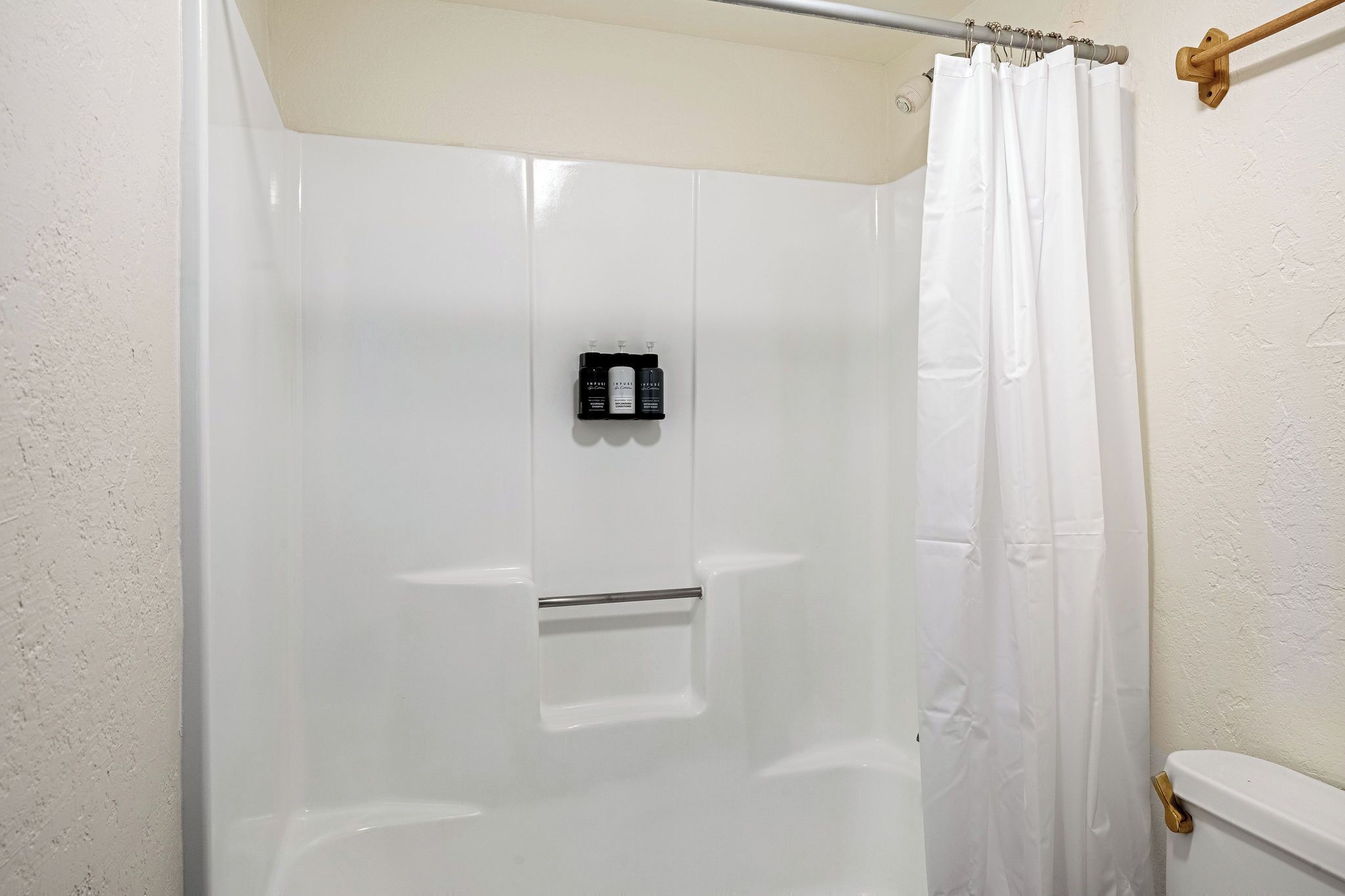 Een witte douchecabine met een glazen deur, een handdoekhouder en een toilet aan de rechterkant.