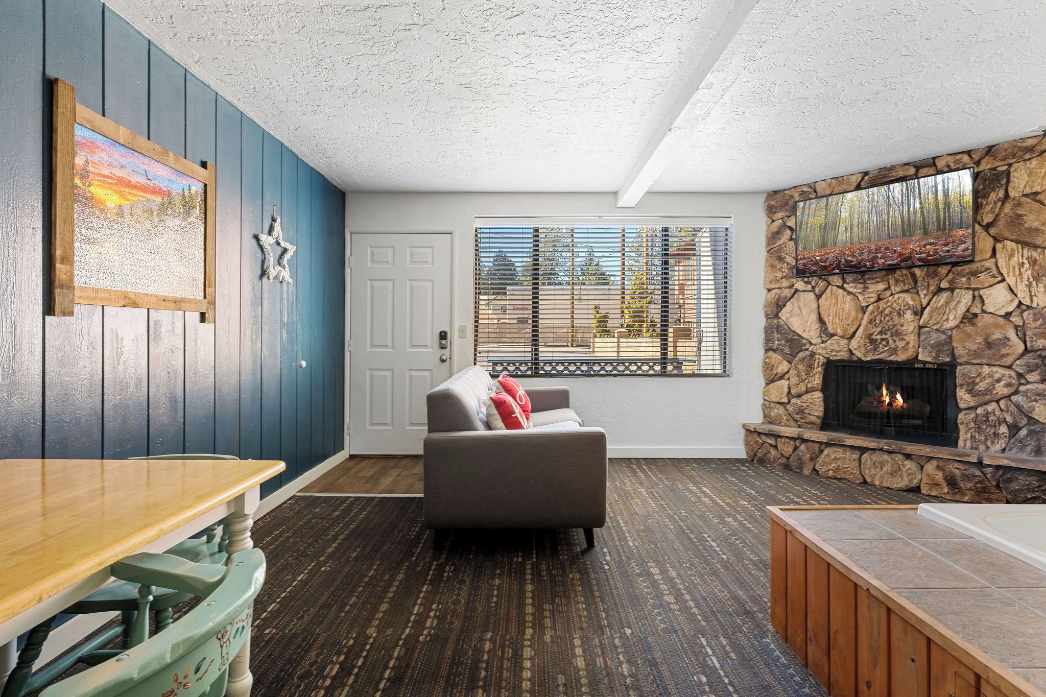 A cozy living room with a stone fireplace, a wooden table, and a comfortable sofa.