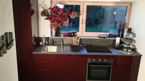 Een moderne keuken met een ingebouwde oven, een roestvrijstalen spoelbak en een raam met uitzicht op bomen.