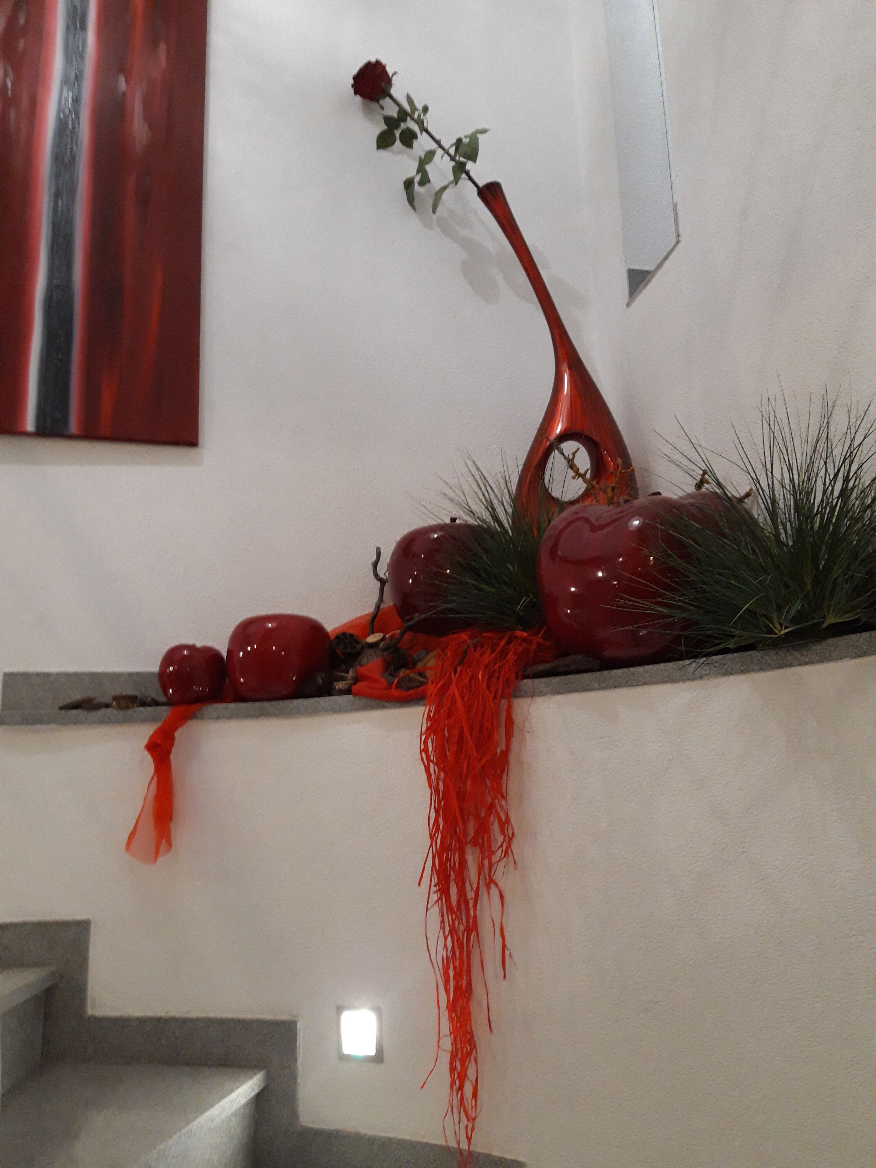 A staircase with a decorative arrangement including a vase, a rose, and red apples.