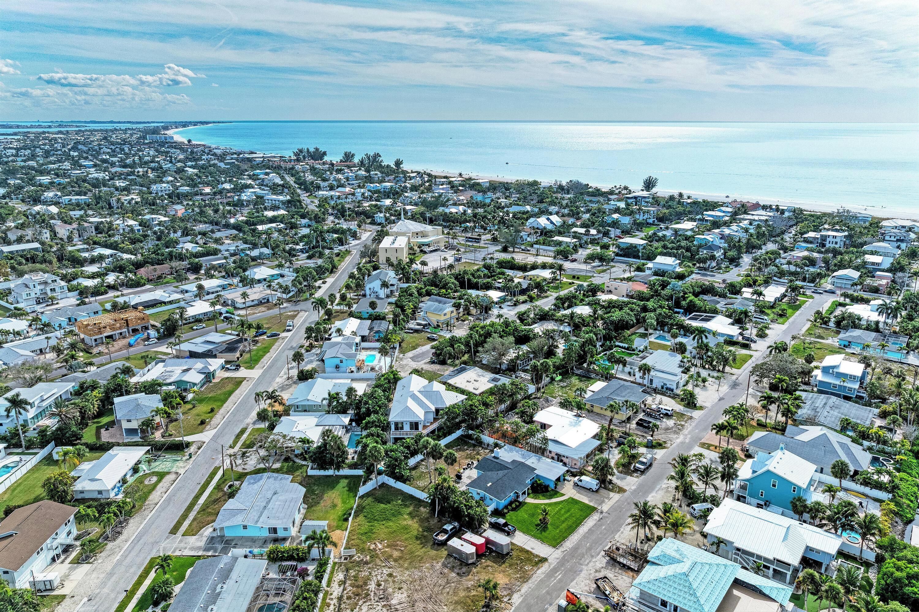 Vue aérienne d’une zone résidentielle côtière, avec des maisons, des routes et une plage.