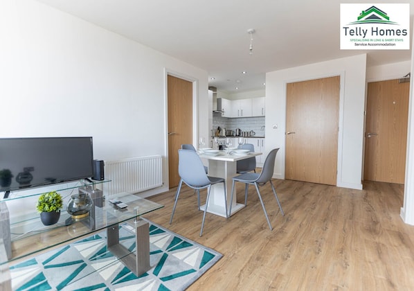 Un appartement moderne comprenant un coin repas, une cuisine et un téléviseur.