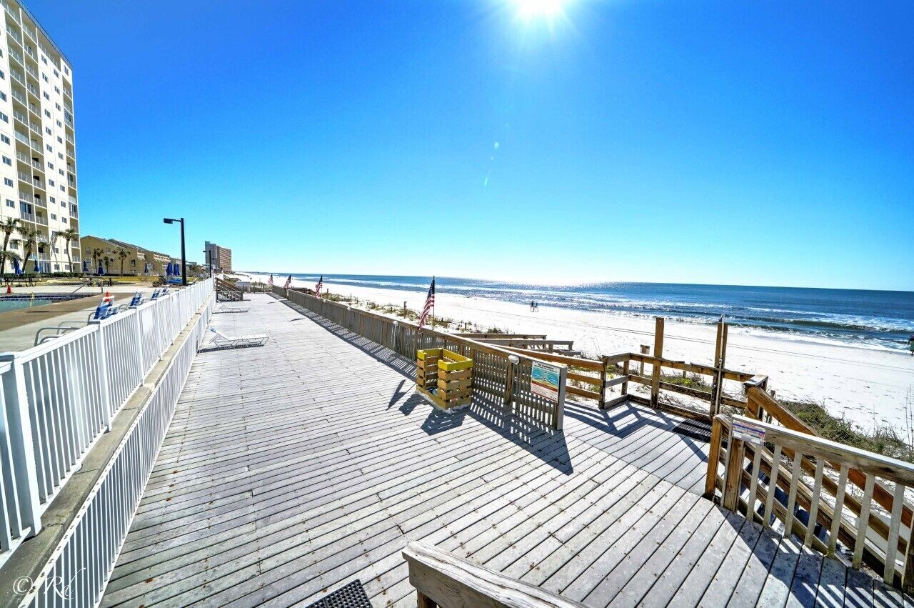 A wooden boardwalk leading to a beach with a clear view of the ocean.