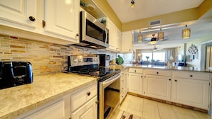 A kitchen with white cabinets, a stainless steel stove, and a microwave.