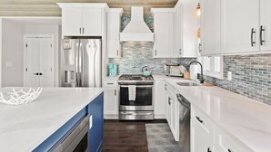 Una cocina moderna con gabinetes blancos, electrodomésticos de acero inoxidable y una pared de acento azul.