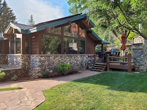 Une cabane en rondins avec des fondations en pierre, de grandes fenêtres et un espace patio.