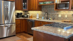 Una cocina moderna con armarios de madera, electrodomésticos de acero inoxidable y encimera de granito.