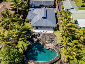 Luftaufnahme eines Hauses mit Swimmingpool, umgeben von Palmen.