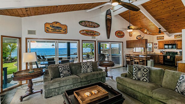 A spacious living area with a view of the ocean, a kitchen, and a dining area with a high ceiling and wooden beams. - Hilo Shangrila - Oceanfront, Pool and Hot Tub Private Vacation Rental (Keaau)