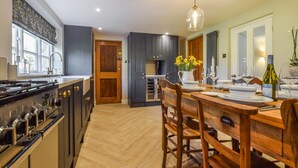 Una cocina moderna con armarios oscuros, una mesa de comedor de madera dispuesta para cuatro personas y un ventanal que proporciona luz natural.