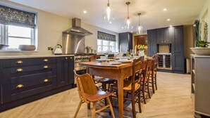 Una cocina moderna con armarios oscuros, electrodomésticos de acero inoxidable y una mesa de comedor de madera.