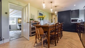 Una cocina moderna con armarios oscuros, una mesa de comedor de madera y lámparas colgantes.