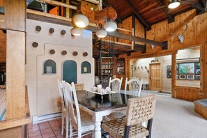 Cozy cabin-style dining area with a large wooden table and pendant lights.