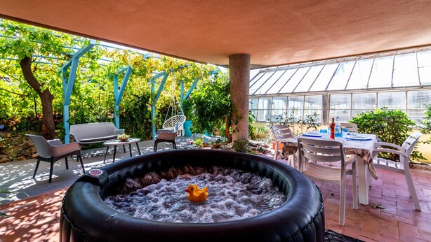 An outdoor hot tub with a rubber duck, surrounded by patio furniture and a greenhouse in the background. - Two Bedroom Apartment (Bordighera)