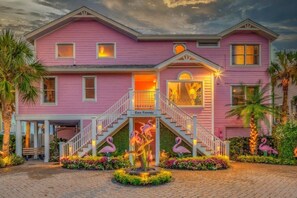 Step into Casa Flamenco's charming two-story home, featuring a central staircase and a beautiful garden with flamingo statues and lush greenery.
