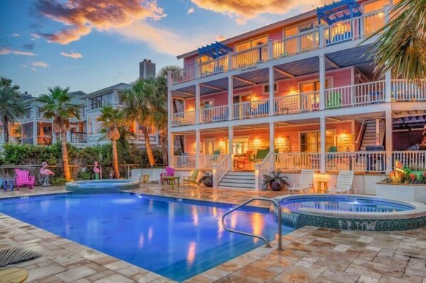Guests can enjoy a pool area with a hot tub, lounge chairs, and palm trees, surrounded by balconies on each floor.