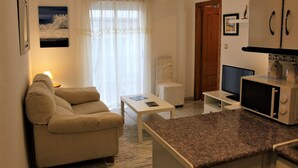 A compact living space with a sofa, a small table, a television, and a microwave. - APARTMENT 2 MINUTES AWAY FROM PUERTA DEL MAR BEACH  (Almuñécar)