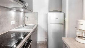 A compact kitchen with a stainless steel range hood, a built-in sink, a double-door refrigerator, and a coffee maker on the countertop. - Le Curling B (Val Claret) by Interhome (Tignes)