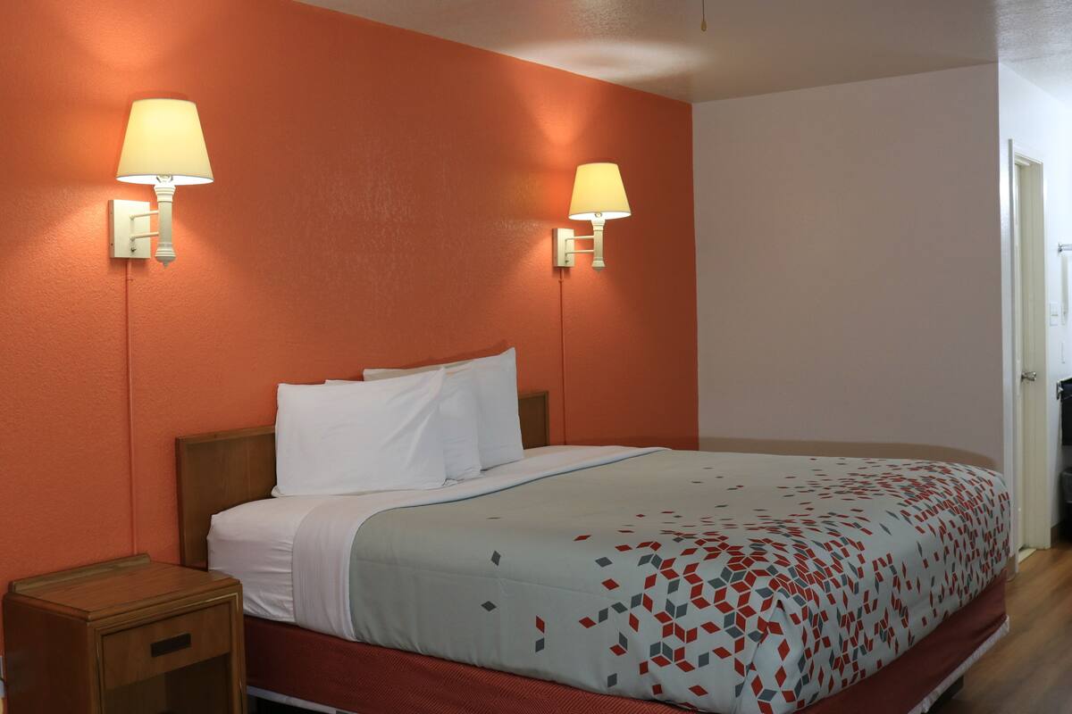 Ein Hotelzimmer mit einem Bett, zwei Wandleuchten und einem Holznachttisch.