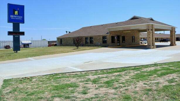 A Heritage Inn & Suites building with a covered parking area and a signboard.