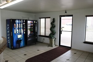 A room with a vending machine, a potted plant, and a door leading outside.