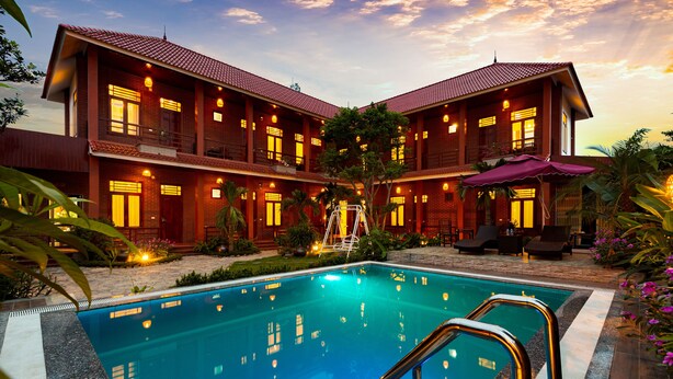 A two-story hotel with a swimming pool, outdoor seating, and a well-lit facade. - Viet Xua Homestay (Ninh Binh)