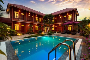 A two-story hotel with a swimming pool, outdoor seating, and a well-lit facade. - Viet Xua Homestay (Hoa Lu)