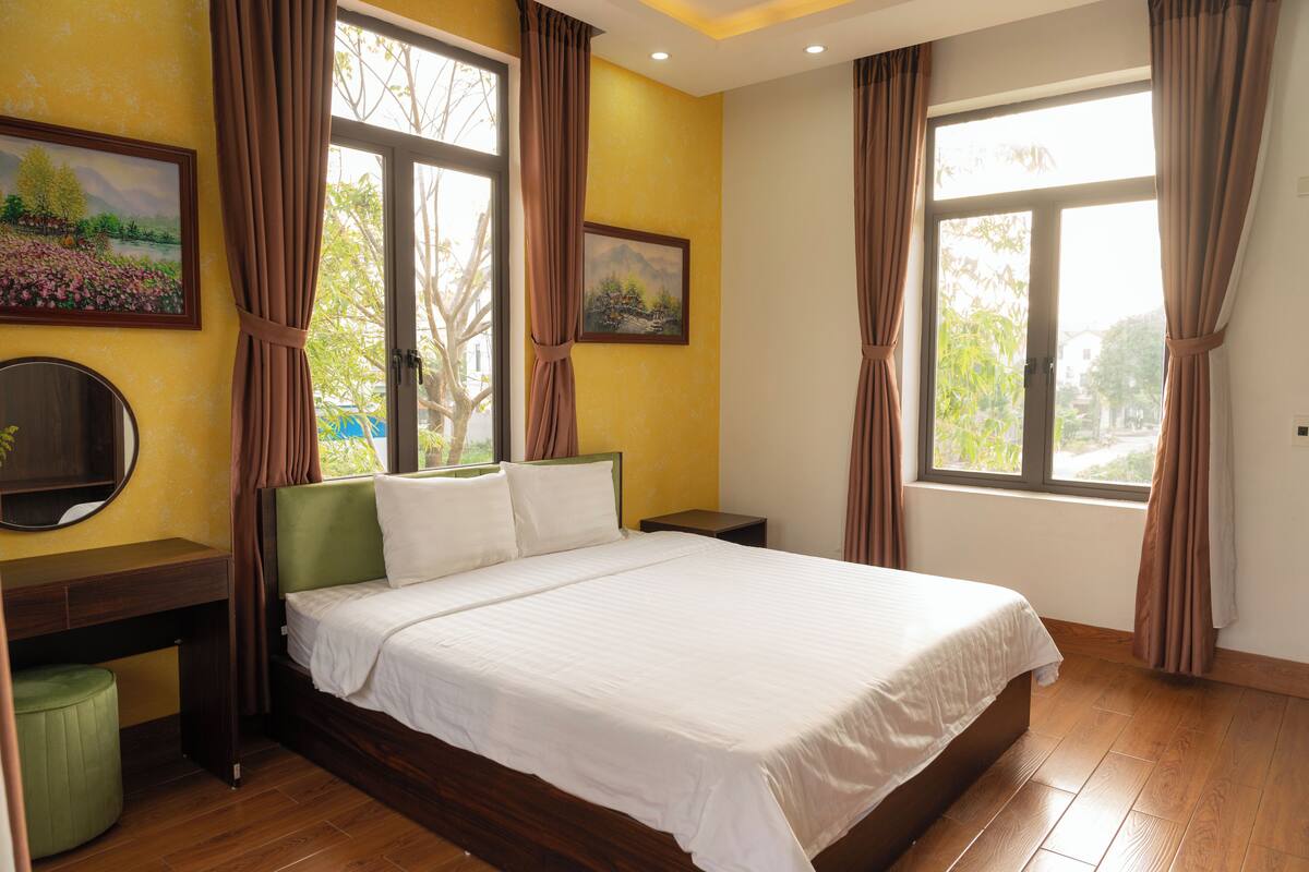 A bedroom with a bed, a desk, a chair, and a window with curtains.
