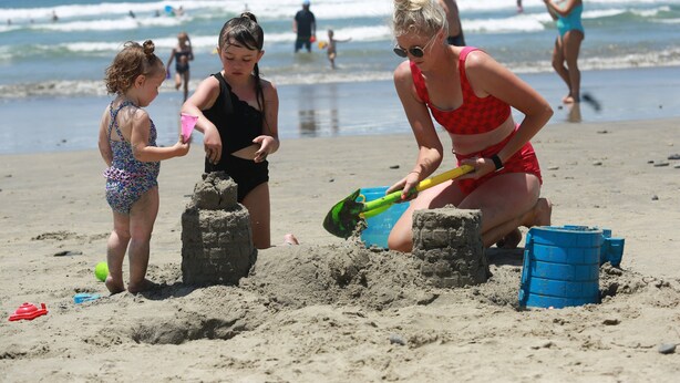 A beach scene with people building sand structures.