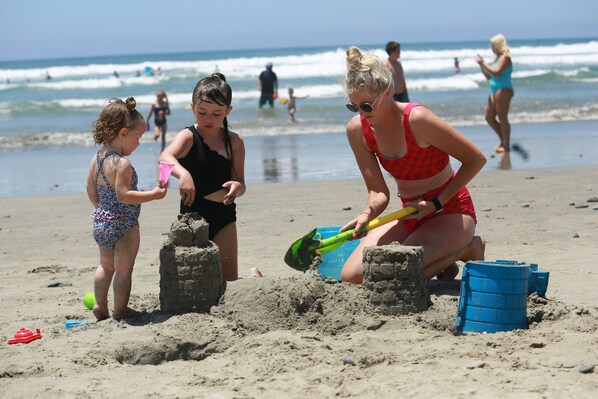A beach scene with people building sand structures.
