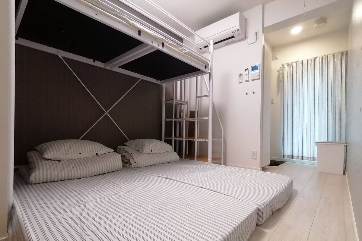 A room with a bed featuring striped bedding, a ceiling fan, and a window with curtains.