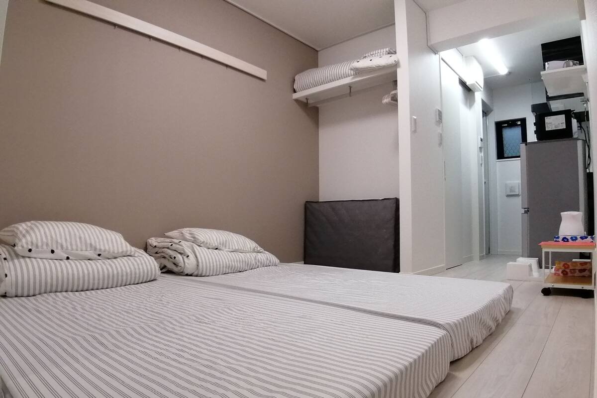 A bedroom with a bed, pillows, a headboard, a bedside table, and a mirror.