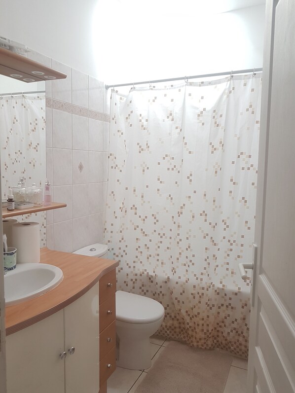 Et badeværelse med toilet, vask og spejl.