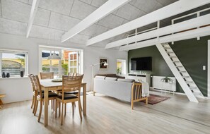 Tilava olohuone, jossa on ruokapöytä ja -tuolit, sohva ja portaikko.