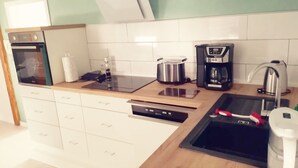 Moderni keittiö, jossa on sisäänrakennettu uuni, kahvinkeitin, vedenkeitin ja astianpesukone.