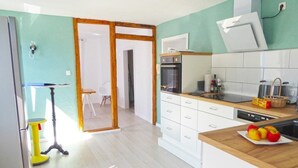 Moderni keittiö, jossa on puinen työtaso, valkoiset kaapit ja sisäänrakennettu uuni.