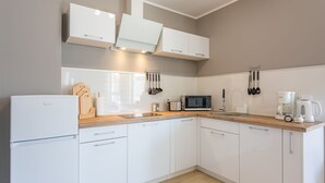 A modern kitchen with white cabinets, a wooden countertop, a built-in microwave, and a coffee maker. - Ferienwohnung am Meer, Urlaub auf der Insel Usedom, Appartement Centrum (Swinoujscie)