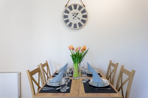 A dining table set with plates, glasses, and a vase of tulips.