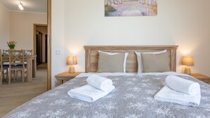 A hotel room with a bed, two nightstands, a wooden headboard, and a painting of a beach scene. - Ferienwohnung am Meer, Urlaub auf der Insel Usedom, Appartement Centrum (Swinoujscie)