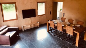 A modern interior with a wooden dining area, a flat-screen TV, and a sofa. - Ferienhaus Baustert (Baustert)