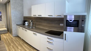 Cozinha moderna com armários brancos, micro-ondas de aço inoxidável e forno embutido.