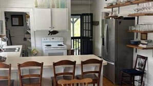 A modern kitchen with white cabinetry, a central island with seating, a ceiling fan, and a dining table with chairs.