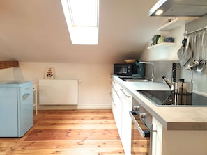 A compact kitchen with a built-in microwave, a small refrigerator, and a sink with modern fixtures.