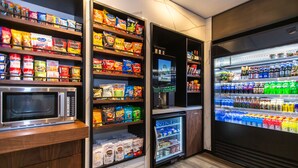Eine Küchenzeile mit Mikrowelle, Regalen voller Snacks, einem Kühlschrank und einem Gefriertruhe.
