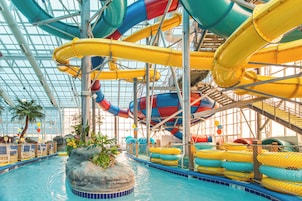An indoor water park with multiple water slides, a pool, and seating areas.