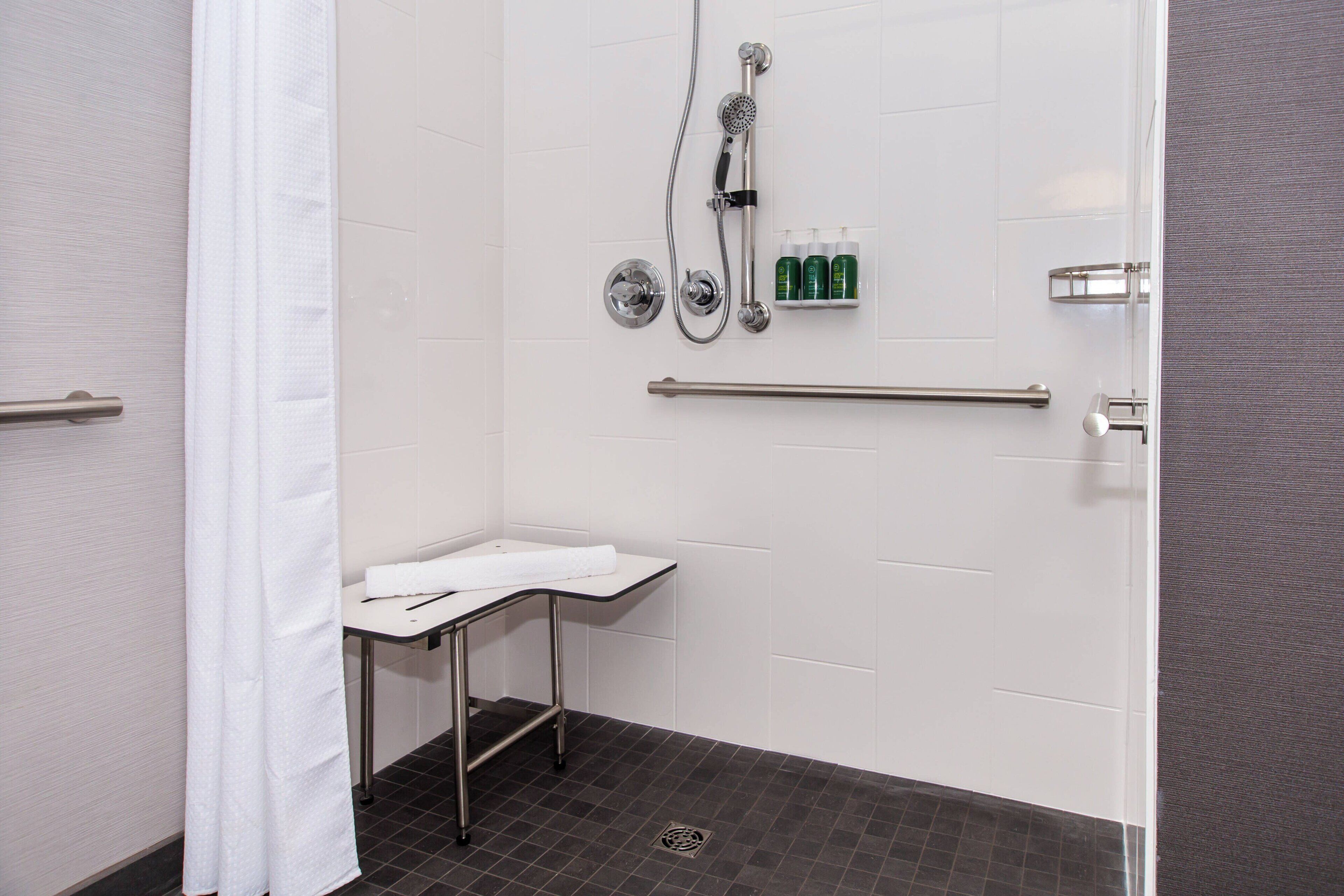 Een moderne badkamer met een douche, een wastafel met een handdoek en toiletartikelen op een plank.